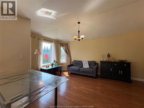 A living room with a glass table and a grey couch.