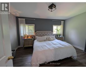 A bedroom with a large bed and a nightstand with a lamp.