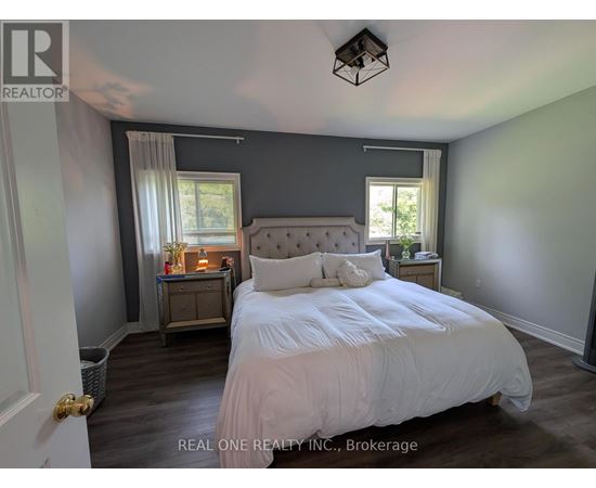 A bedroom with a large bed and a nightstand with a lamp.