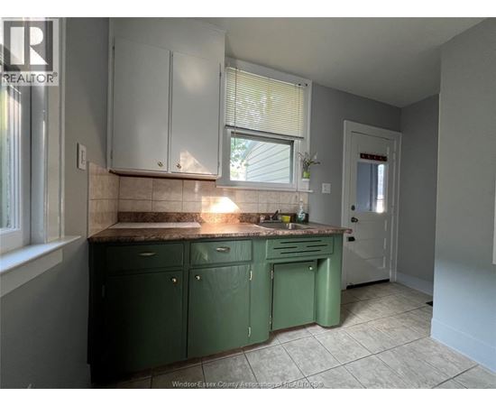 A kitchen with green cabinets and a tiled floor.
