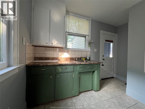 A kitchen with green cabinets and a tiled floor.