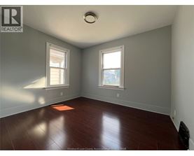 A room with a wooden floor and two windows.