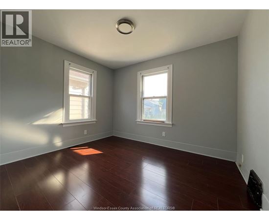 A room with a wooden floor and two windows.