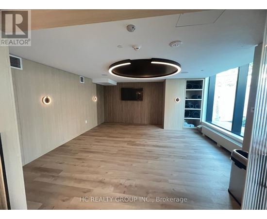 A spacious room with wooden flooring and a large window on the right side.
