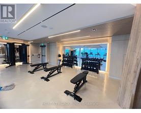 A gym with a row of black benches and weights.