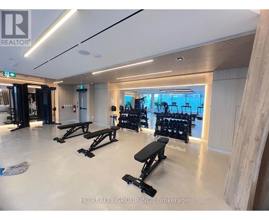 A gym with a row of black benches and weights.