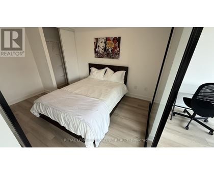 A bedroom with a white bed and a black chair.
