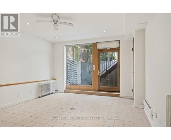 A spacious room with a ceiling fan and sliding glass doors leading to a balcony.
