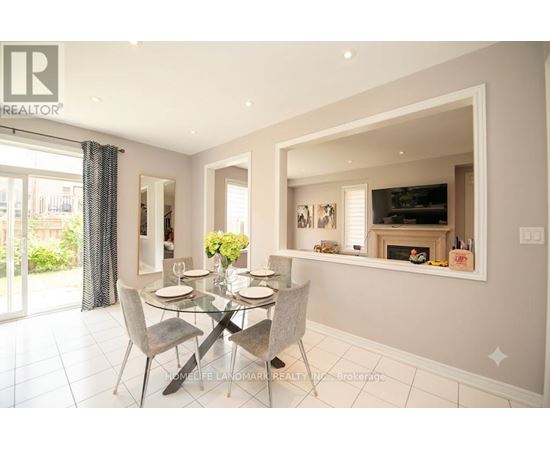 A dining room with a glass table and grey chairs.