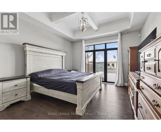 A bedroom with a large bed, wooden floors, and a dresser with a mirror.