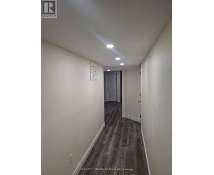 A hallway with wood flooring and white walls.