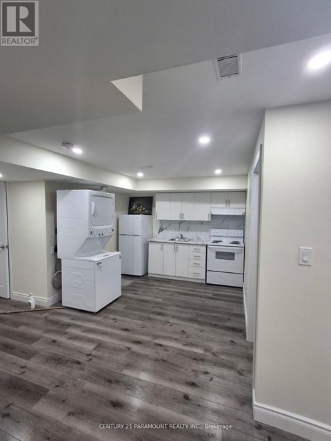 A kitchen with white appliances and wood flooring.