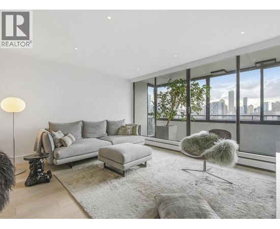 A modern living room with a grey sofa and a view of the city.