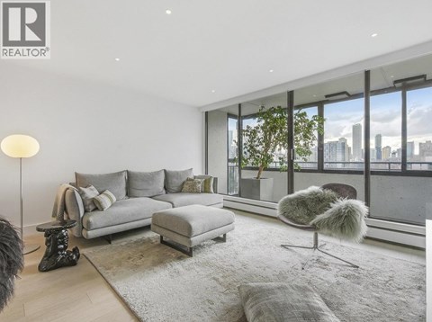 A modern living room with a grey sofa and a view of the city.