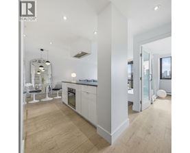 A modern kitchen with white cabinets and a wooden floor.