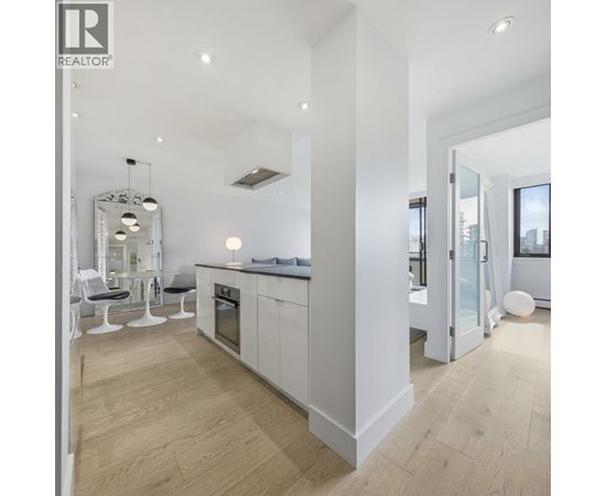 A modern kitchen with white cabinets and a wooden floor.