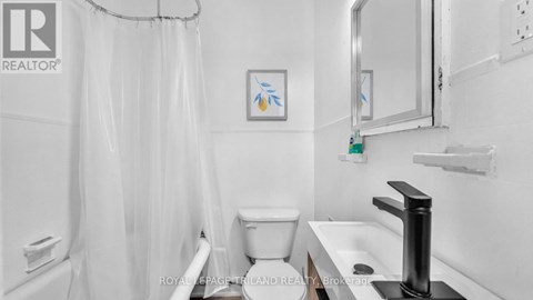 A white bathroom with a toilet, sink, and shower curtain.