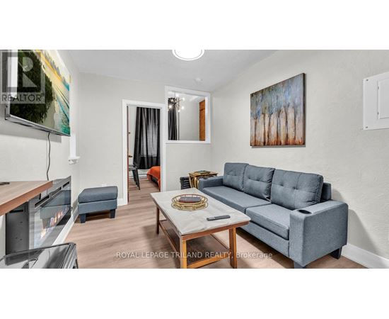 A living room with a grey couch and a painting on the wall.