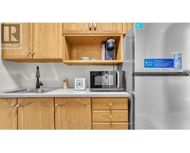 A kitchen with wooden cabinets and a refrigerator with a sign on it.