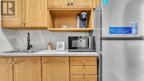 A kitchen with wooden cabinets and a refrigerator with a sign on it.