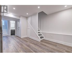 A spacious room with a staircase leading to the upper level.