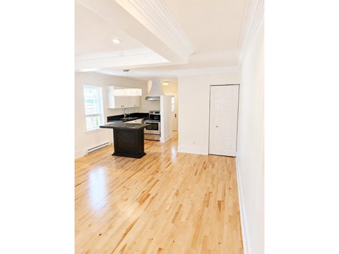 A kitchen with a black stove top oven and wooden floors.