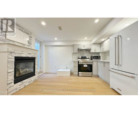A modern kitchen with white cabinets and a stone fireplace.