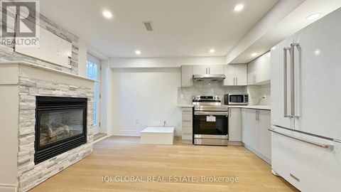 A modern kitchen with white cabinets and a stone fireplace.