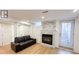 A living room with a stone fireplace and a black leather couch.