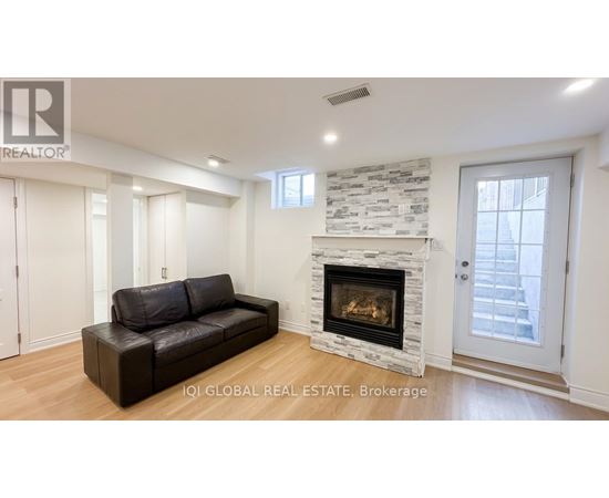 A living room with a stone fireplace and a black leather couch.