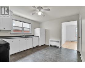 A kitchen with white cabinets and a black trash can.