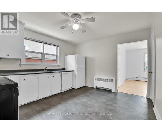 A kitchen with white cabinets and a black trash can.