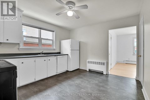 A kitchen with white cabinets and a black trash can.