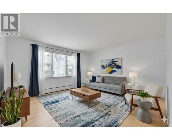 A living room with a grey couch, a coffee table, and a painting on the wall.