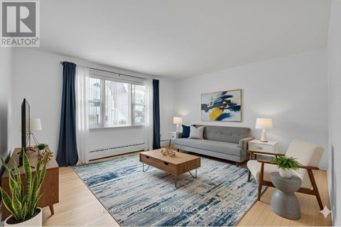 A living room with a grey couch, a coffee table, and a painting on the wall.