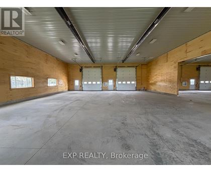 A large empty warehouse space with wooden walls and concrete floor.