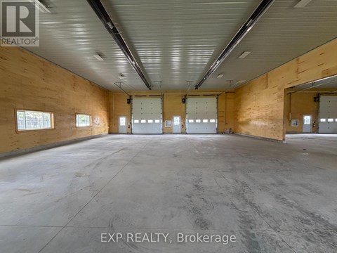 A large empty warehouse space with wooden walls and concrete floor.