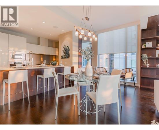 A modern kitchen with white chairs and a glass table.