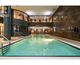 A large indoor swimming pool with a stone wall and a glass divider.