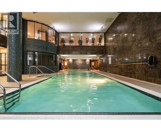 A large indoor swimming pool with a stone wall and a glass divider.