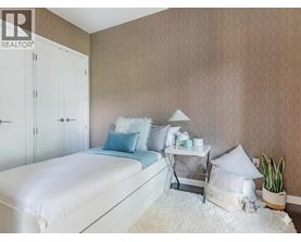 A bedroom with a white bed and a white nightstand with a plant on it.