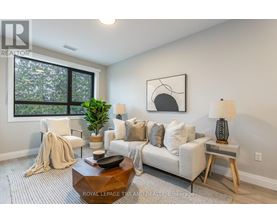 A living room with a white couch, a coffee table, and a large window.