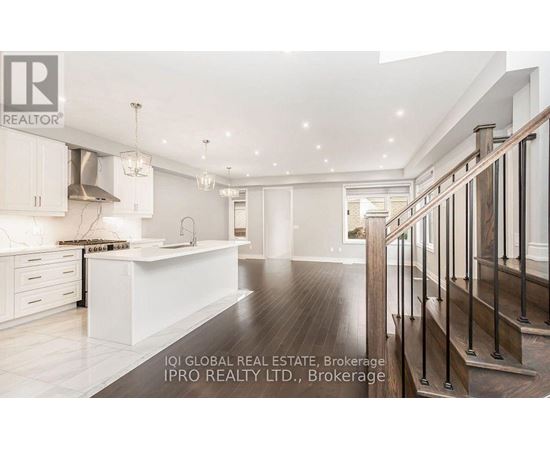 A spacious kitchen with white cabinets and a wooden staircase.