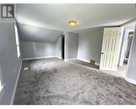 A spacious room with a carpeted floor and a white door.