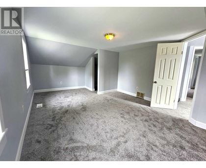 A spacious room with a carpeted floor and a white door.