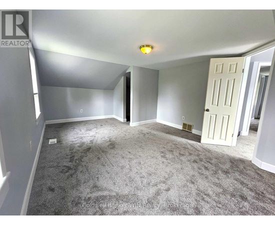 A spacious room with a carpeted floor and a white door.