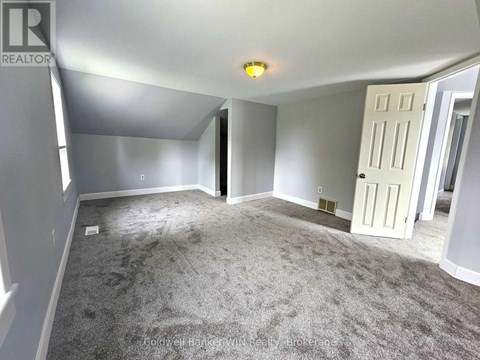 A spacious room with a carpeted floor and a white door.