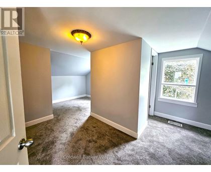 A room with a carpeted floor and a window showing trees outside.