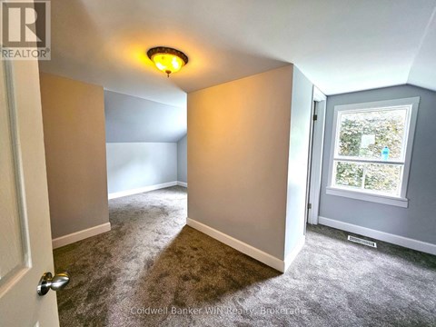 A room with a carpeted floor and a window showing trees outside.