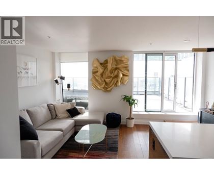 A living room with a couch, a table, and a large sculpture on the wall.